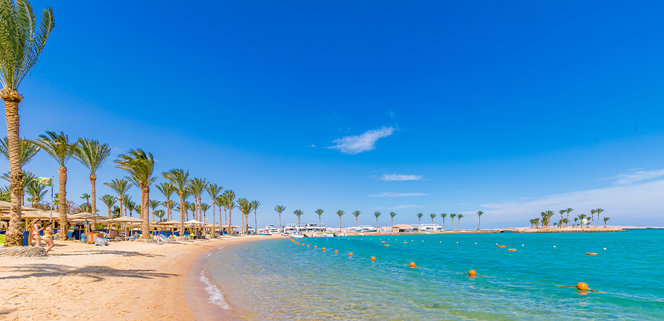 Vue panoramique de la plage privée du club Framissima Hurghada bordée de palmiers en Égypte